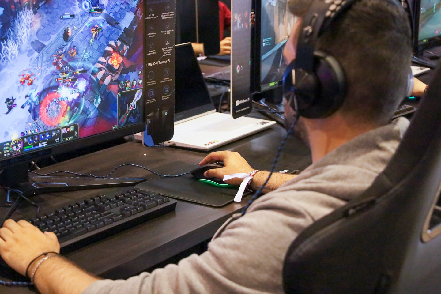 Un jugador con auriculares juega un videojuego de fantasía en un monitor.